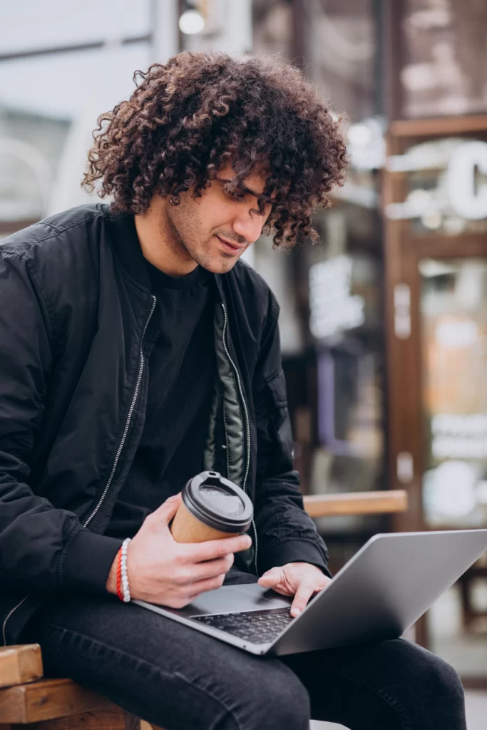 handsome student with curly hair using laptop